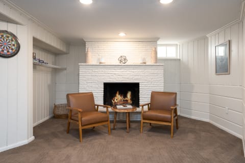 Living room with a white brick fireplace and mid-century modern chairs.