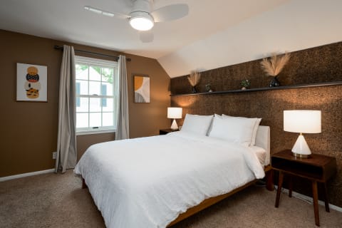 Cozy bedroom featuring a queen bed, wooden nightstand, and decorative wall art.