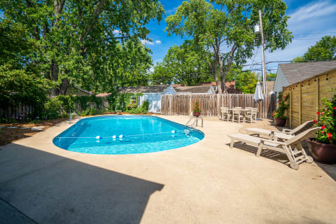 Bright swimming pool in a lush backyard with lounge chairs and vibrant flowers.
