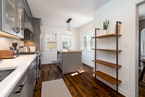 A contemporary kitchen featuring grey cabinets, a wooden island, and open shelves.