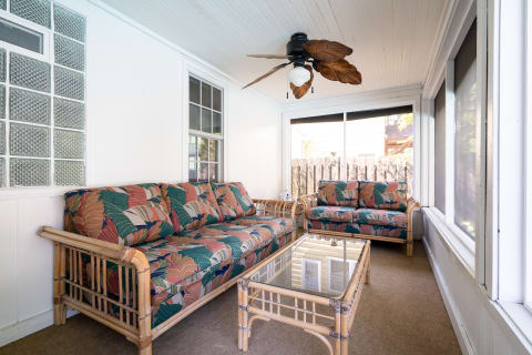 A cozy sunroom featuring colorful rattan furniture and natural light.