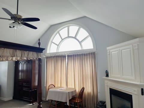 Bright living room with an arched window, wood table, and light curtains.