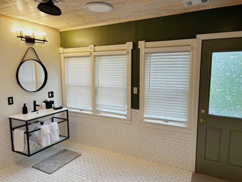 Contemporary bathroom with large windows, a floating vanity, and stylish decor.