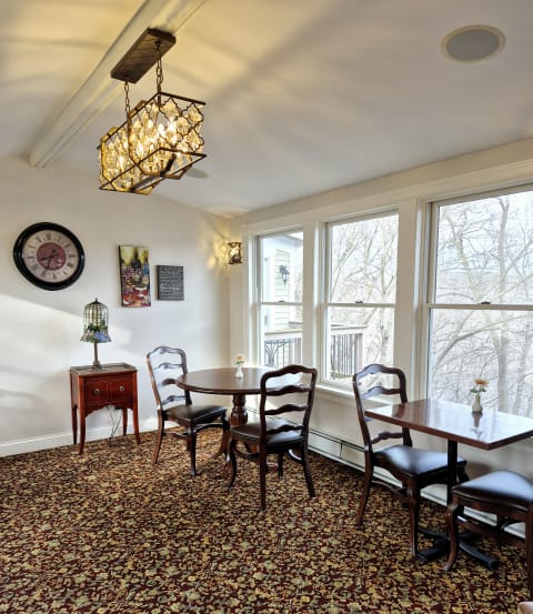 Cozy dining room featuring a chandelier, wooden furniture, and large windows overlooking nature.