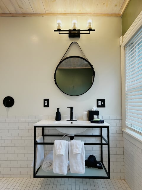 Modern bathroom with round mirror, stylish sink, and plush towels.