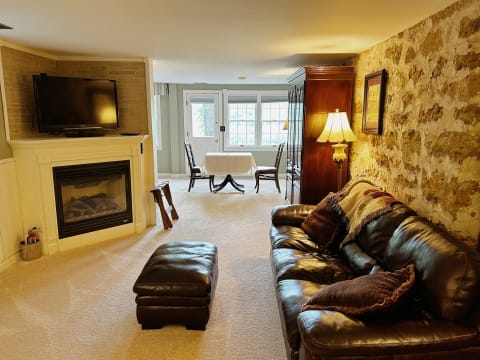 A cozy living room with a leather sofa, fireplace, and large windows, evoking a warm ambiance.