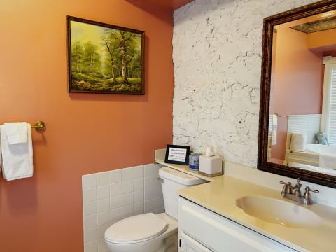 Charming bathroom with rustic decor, featuring a painting, white towels, and a countertop with a sink and amenities.