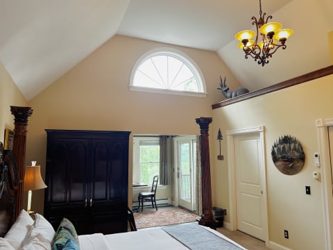 An elegant bedroom with vaulted ceilings, dark wood furniture, and a balcony view.