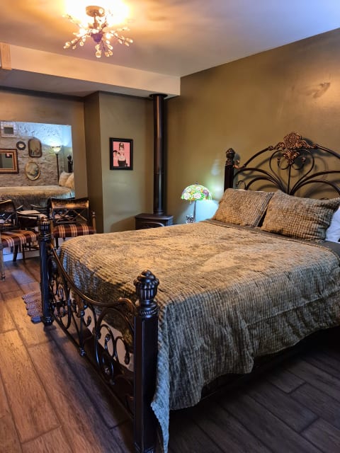 A cozy bedroom featuring a wrought-iron bed with quilted bedding, a chandelier, and stylish decor.