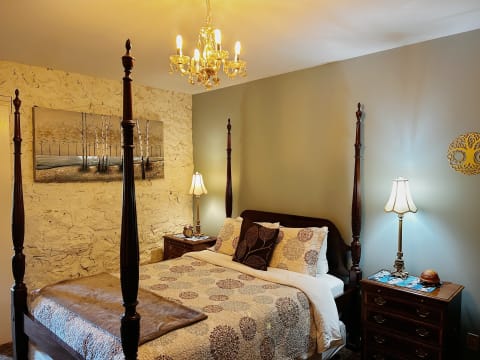A cozy four-poster bed in a warmly lit bedroom with decorative lamps and artwork.