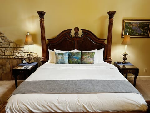 Luxurious four-poster bed with ornate headboard and decorative pillows in a warmly lit bedroom.