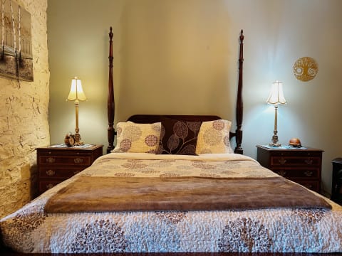 A beautifully arranged bedroom featuring a four-poster bed with intricate bedding and warm bedside lamps.