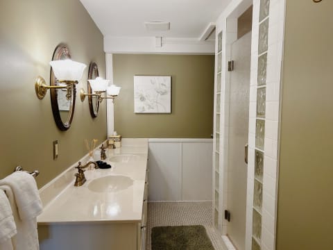 Elegant bathroom with warm lighting, marble countertops, and a spacious glass-enclosed shower.