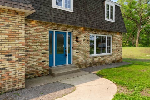 A welcoming house entrance featuring a blue door and a brick exterior.