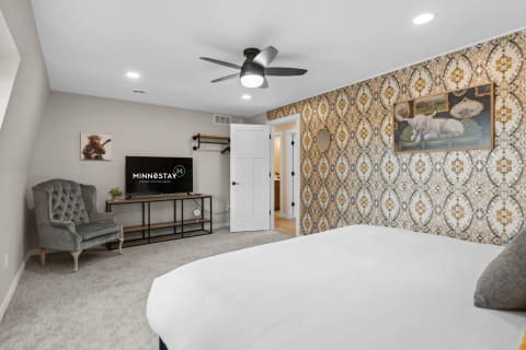 Stylish bedroom featuring patterned wallpaper, a flat-screen TV, and modern decor.