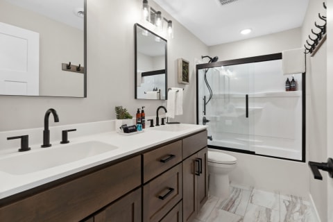 Modern bathroom with a double vanity, black fixtures, and glass shower.