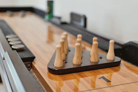 Close-up of a shuffleboard table with wooden game pieces in a triangular scoring area.