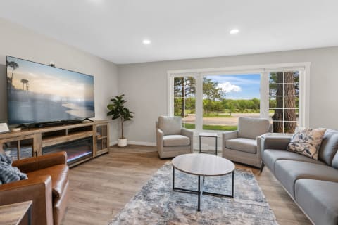 A spacious living room featuring a large window, contemporary furniture, and a flat-screen TV.