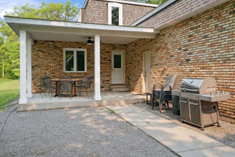 Outdoor patio area with dining table, chairs, and a barbecue grill.