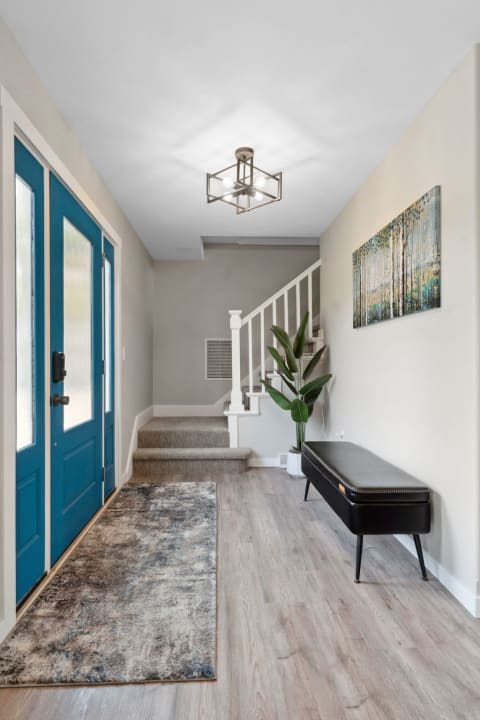 Stylish entryway with blue double doors, a staircase, and contemporary decor.
