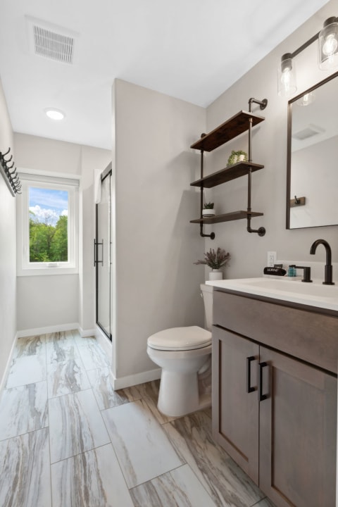 Contemporary bathroom with a shower, vanity, and natural light from a window.
