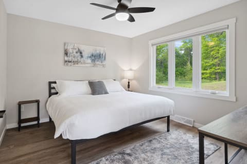 Modern bedroom featuring a king-sized bed, natural light from a window, and minimalist decor.