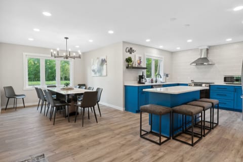 A modern kitchen with blue cabinets and a dining area with a long table and chandelier.