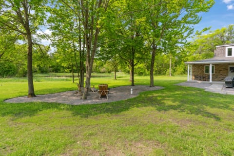 Outdoor seating area with wooden chairs and trees in a green lawn.