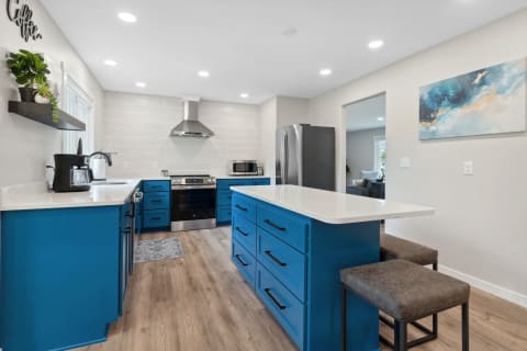 Modern kitchen featuring blue cabinets, a white countertop, and stainless steel appliances.