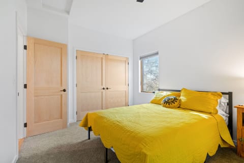 A cozy bedroom featuring a yellow quilted bedcover and natural wood accents.
