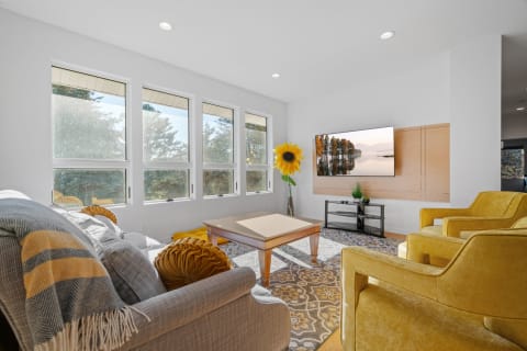 Modern living room featuring gray sofas, yellow chairs, a coffee table, and bright windows.