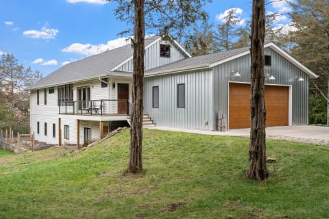 Contemporary house with a mix of white wood and silver metal siding under a blue sky.