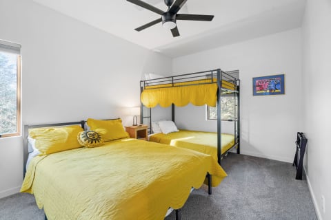 A bright bedroom featuring a bunk bed and a double bed with yellow bedding.