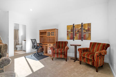 Inviting workspace featuring striped plush chairs, a wooden desk, and bright natural light.
