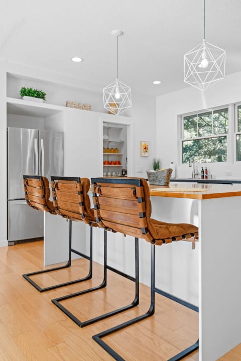A bright kitchen with leather barstools and white decor.