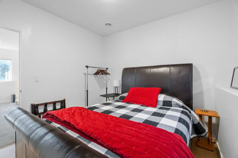 A cozy bedroom with a large leather bed and a red throw blanket.