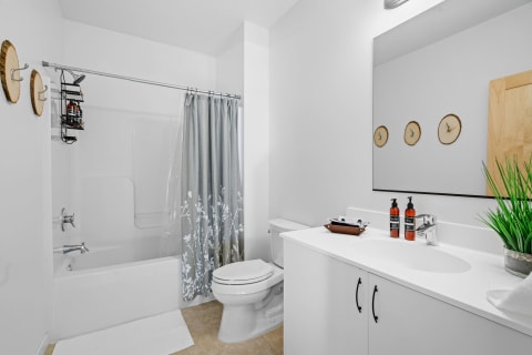 A clean and modern bathroom featuring a white tub, gray shower curtain, and stylish decor.