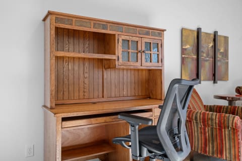 Wooden desk with hutch and ergonomic chair in a cozy workspace.