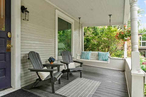 Cozy front porch with two chairs, a swing, and plants.