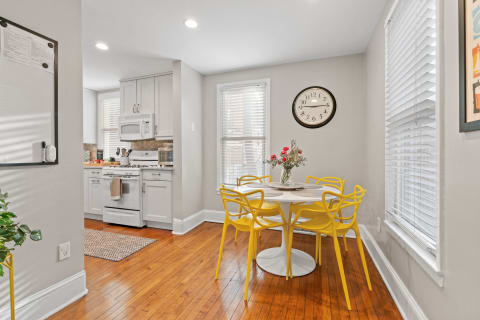 Bright kitchen space featuring white cabinets and yellow dining chairs.