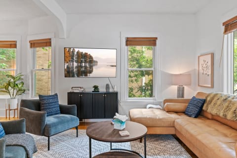 Cozy living room with leather sofa, coffee table, and large windows.