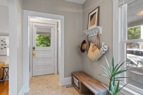 A modern entryway with a bench, coat rack, and natural light from the door.