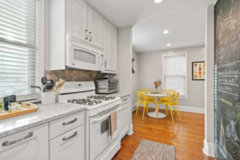 Modern kitchen with yellow chairs, a round table, and white cabinetry.