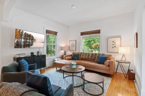 Stylish living room with leather sofa, decorative pillows, and large windows.
