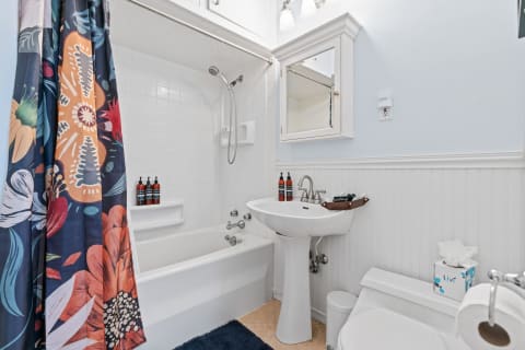 A colorful bathroom with a floral shower curtain, white sink, and modern decor.