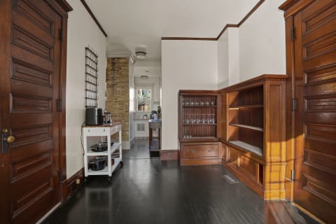 Interior view of a butler's pantry showcasing wooden cabinetry, glassware, and cooking essentials on a cart.