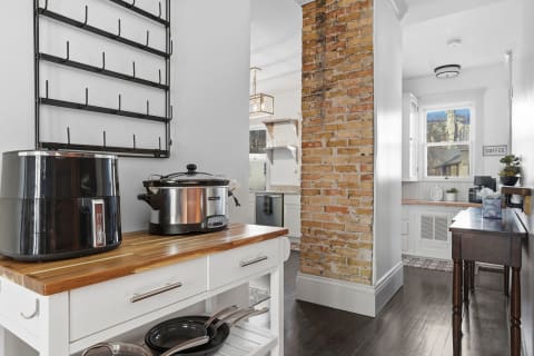 A modern kitchen featuring an air fryer, a slow cooker, and a brick accent wall.