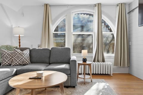 Cozy living room with a gray sectional sofa and large arched windows.
