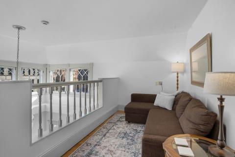 Cozy upstairs living nook featuring a brown sectional sofa, intricate area rug, and warm lighting.
