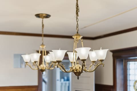 Brass chandeliers with frosted glass shades illuminating a dining area.